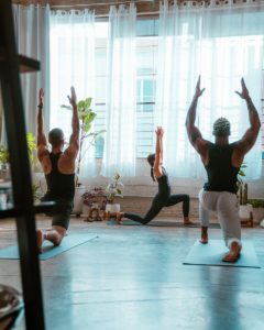Cours de yoga avec 3 personnes qui pratique la posture Anjaneyasana - La Fente Basse